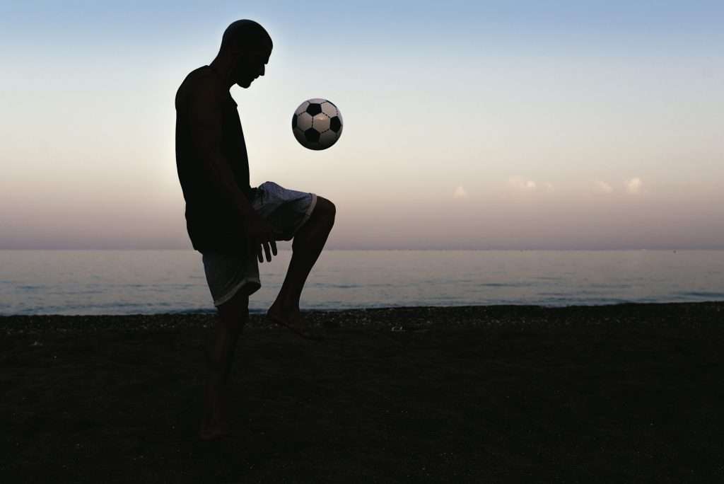 Man playing soccer in the beach