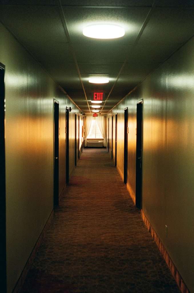 Empty Corridor with exit board in red light written on top