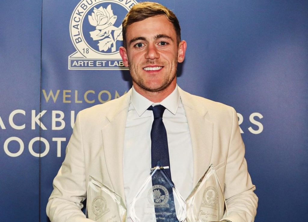 Sammie Szmodics holding trophy in white coat.